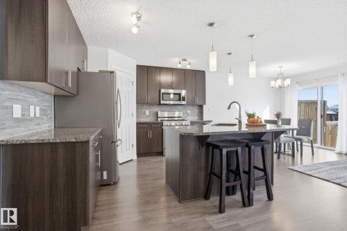 The property features an open-concept kitchen with dark wood cabinetry, granite countertops, and stainless steel appliances - 2553 Coughlan Road, Edmonton, AB - Indoor Photo Showing Kitchen With Upgraded Kitchen