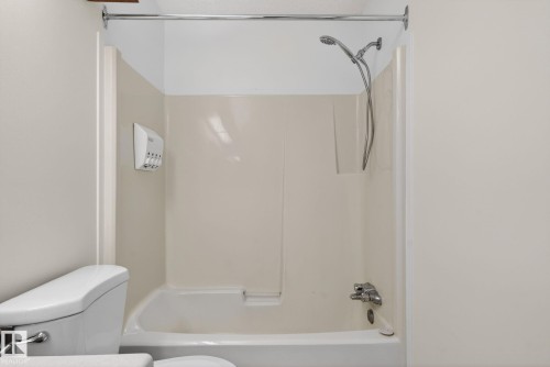 Bathtub with integrated shower surround, featuring a chrome shower head with handheld sprayer and a chrome tub filler - 18604 97A Avenue, Edmonton, AB - Indoor Photo Showing Bathroom