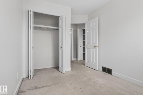 Light-toned carpeting grounding a room featuring white walls and trim, with a bi-fold closet door revealing storage space - 18604 97A Avenue, Edmonton, AB - Indoor Photo Showing Other Room