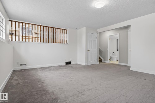 Carpeted room with a partial height wall featuring wood balusters and a white painted railing - 18604 97A Avenue, Edmonton, AB - Indoor Photo Showing Other Room