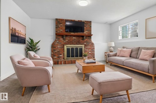 Living area featuring a floor-to-ceiling brick fireplace with a wood mantel, a built-in television mount, and a gold-toned firebox - 18604 97A Avenue, Edmonton, AB - Indoor Photo Showing Living Room With Fireplace