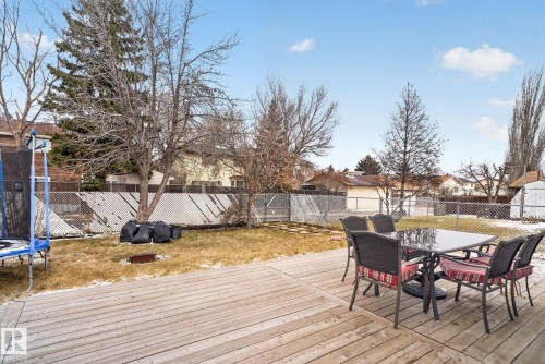Expansive backyard featuring a wood deck, mature trees, chain-link fencing, and a storage shed - 18604 97A Avenue, Edmonton, AB - Outdoor With Deck Patio Veranda