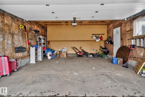 Attached two-car garage featuring a concrete floor, exposed insulation, a side access door, and overhead lighting - 18604 97A Avenue, Edmonton, AB - Indoor Photo Showing Garage