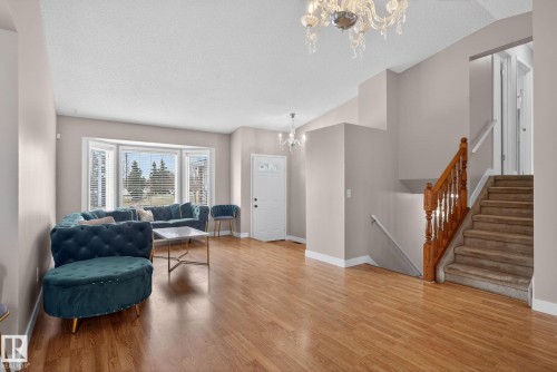 Open-concept living area featuring wood-finish flooring, a prominent bay window with blinds, and a white front entry door with decorative glass - 18604 97A Avenue, Edmonton, AB - Indoor Photo Showing Living Room