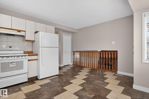 Kitchen area featuring white cabinetry with wood trim accents, light wood-finish countertops, and a white tile backsplash - 18604 97A Avenue, Edmonton, AB - Indoor Photo Showing Kitchen