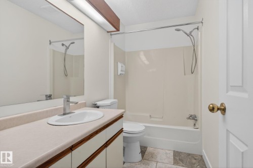 Full bathroom with wood-finish vanity, light-toned countertop, and integrated sink - 18604 97A Avenue, Edmonton, AB - Indoor Photo Showing Bathroom