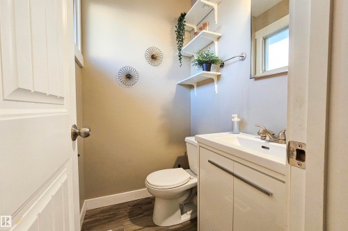 Bathroom featuring a white vanity with integrated sink, brushed nickel faucet, wood-finish flooring, and white floating shelves - 4203 83 Street, Edmonton, AB - Indoor Photo Showing Bathroom