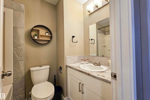 Bathroom featuring a white vanity with a light-toned countertop, an integrated sink, and an overhead vanity light fixture - 4203 83 Street, Edmonton, AB - Indoor Photo Showing Bathroom