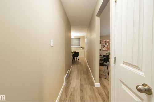 Hallway with wood-finish flooring, light tan wall paint, and white baseboards - 4203 83 Street, Edmonton, AB - Indoor Photo Showing Other Room