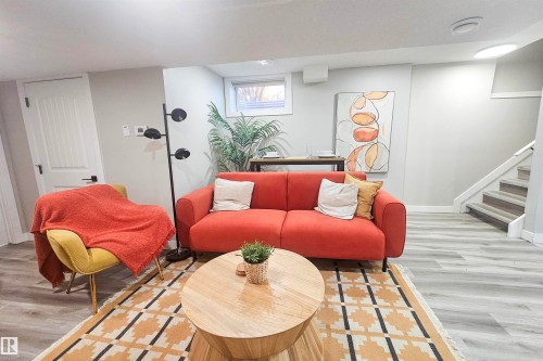 Spacious living area featuring light-toned wood-finish flooring, a contemporary staircase with white risers, and a prominent window providing natural illumination - 4203 83 Street, Edmonton, AB - Indoor