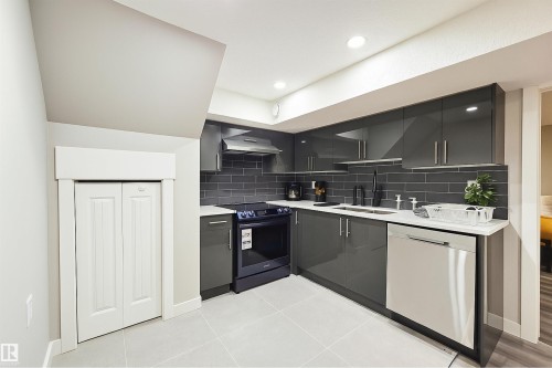 Contemporary kitchen featuring dark grey cabinetry, white countertops, and a subway tile backsplash - 4203 83 Street, Edmonton, AB - Indoor