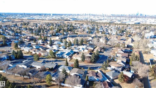 Expansive aerial view showcasing a residential neighborhood with numerous detached homes, mature trees, and a distant city skyline - 4203 83 Street, Edmonton, AB - Outdoor With View