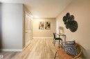 Hallway featuring wood-finish flooring, light-colored walls, white baseboards, and a white paneled door with brushed nickel hardware - 4203 83 Street, Edmonton, AB  - Indoor Photo Showing Other Room 