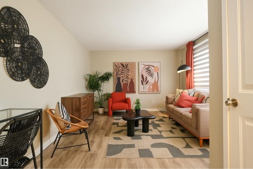 Spacious living area featuring wood-finish flooring, neutral wall tones, and a large window with privacy blinds - 4203 83 Street, Edmonton, AB - Indoor