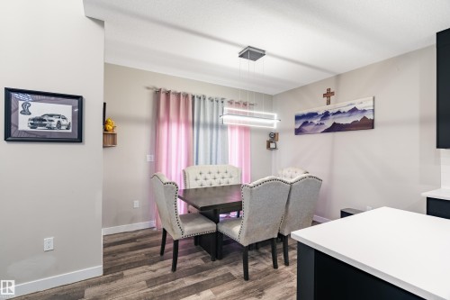 Dining area featuring wood-finish flooring, a contemporary linear chandelier, and light gray wall paint - 2 Edison Drive, St. Albert, AB - Indoor Photo Showing Other Room