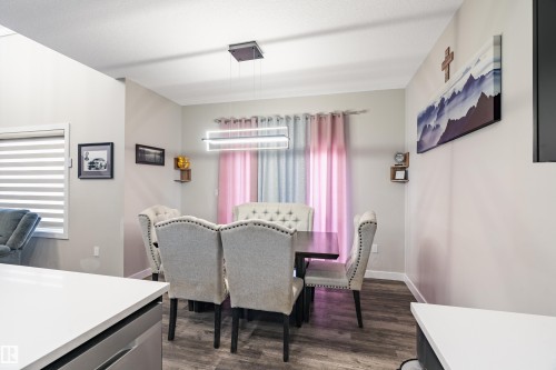 Dining area featuring wood-finish flooring, a contemporary linear chandelier, and light-toned walls - 2 Edison Drive, St. Albert, AB - Indoor Photo Showing Dining Room
