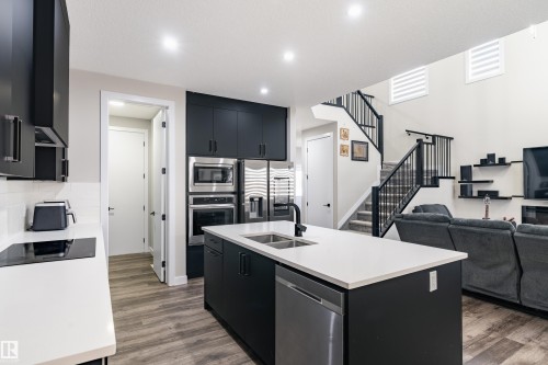 Modern kitchen featuring dark cabinetry, stainless steel appliances, and light countertops - 2 Edison Drive, St. Albert, AB - Indoor Photo Showing Kitchen With Double Sink