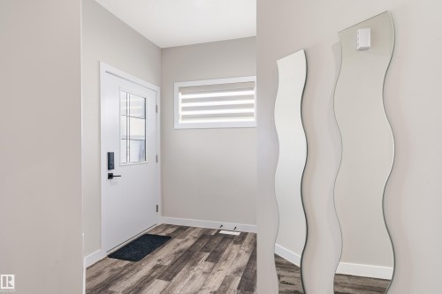 Foyer with wood-finish flooring, a white entry door with an integrated window, and a transom window with horizontal blinds - 2 Edison Drive, St. Albert, AB - Indoor Photo Showing Other Room