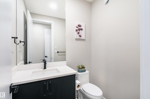Bathroom featuring a dark vanity with a white countertop, undermount sink, and a black faucet - 2 Edison Drive, St. Albert, AB - Indoor Photo Showing Bathroom