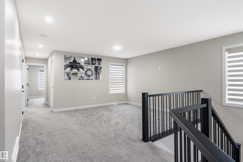 Spacious upper-level landing featuring plush grey carpeting, abundant natural light from two windows with horizontal blinds, and recessed lighting - 2 Edison Drive, St. Albert, AB - Indoor Photo Showing Other Room