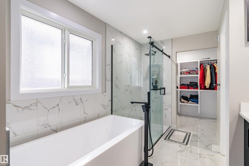 Freestanding tub with floor-mounted faucet, glass-enclosed shower with matte black fixtures, and custom built-in shelving - 2 Edison Drive, St. Albert, AB - Indoor Photo Showing Bathroom