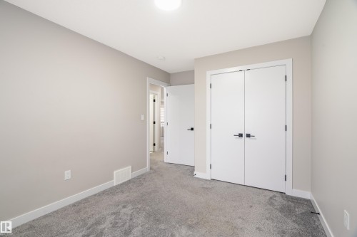 Spacious room featuring neutral paint, gray carpeting, a double-door closet with black hardware, and white trim - 2 Edison Drive, St. Albert, AB - Indoor Photo Showing Other Room
