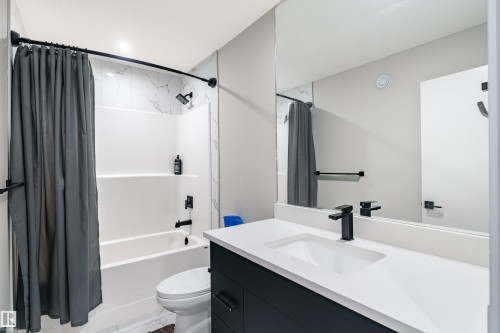 Bathroom featuring a dark vanity with integrated sink, a white countertop, and matte black fixtures - 2 Edison Drive, St. Albert, AB - Indoor Photo Showing Bathroom