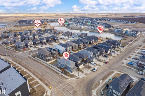 Aerial view of a residential community featuring a variety of housing styles, paved streets, and a prominent pond with surrounding green spaces - 2 Edison Drive, St. Albert, AB - Outdoor With View