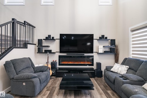 Living area featuring wood-finish flooring, a contemporary electric fireplace, and high ceilings - 2 Edison Drive, St. Albert, AB - Indoor