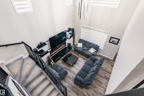 Two-story living area featuring wood-finish flooring and a contemporary linear chandelier - 2 Edison Drive, St. Albert, AB - Indoor