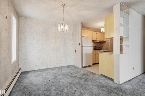 Dining area featuring a decorative chandelier, baseboard heating, and a window - 701 10135 116 Street Nw, Edmonton, AB - Indoor Photo Showing Kitchen