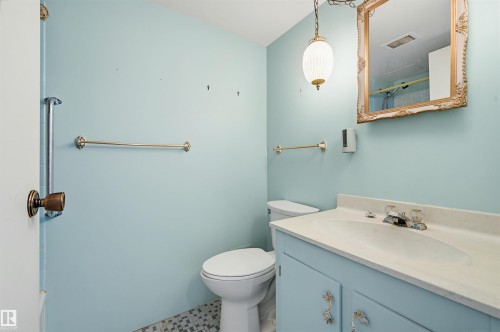 Bathroom with a light blue vanity and an integrated sink, featuring a decorative gold-framed mirror and a pendant light fixture - 701 10135 116 Street Nw, Edmonton, AB - Indoor Photo Showing Bathroom