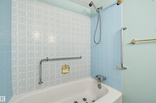 Bathtub with light blue tiled surround, patterned accent tiling, and chrome grab bars - 701 10135 116 Street Nw, Edmonton, AB - Indoor Photo Showing Bathroom