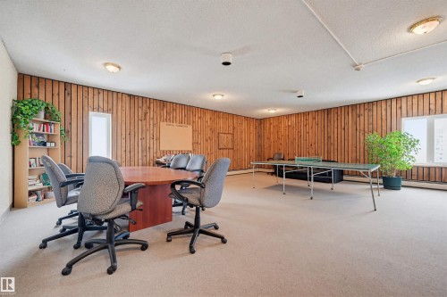 Spacious room featuring paneled walls, neutral carpet, and recessed lighting - 701 10135 116 Street Nw, Edmonton, AB - Indoor Photo Showing Other Room