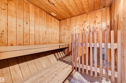 Dedicated sauna room featuring wood-paneled walls and ceiling, multi-tiered wood bench seating, a wood slatted heater guard, and a tiled floor - 701 10135 116 Street Nw, Edmonton, AB - Indoor Photo Showing Other Room