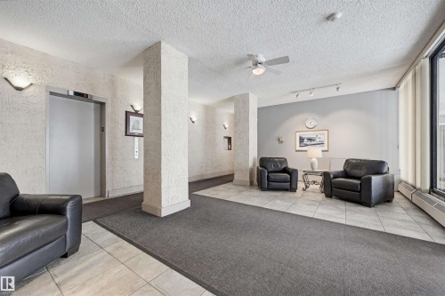 Building common area featuring a wall-mounted elevator, textured wall finishes, and a ceiling fan - 701 10135 116 Street Nw, Edmonton, AB - Indoor