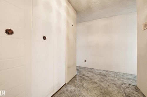 Integrated storage cabinetry featuring decorative hardware, neutral wall finishes, and textured carpeting - 701 10135 116 Street Nw, Edmonton, AB - Indoor Photo Showing Other Room