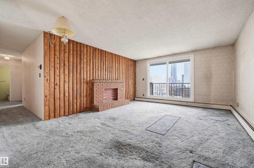 Living area featuring a brick fireplace, wood panel accent wall, and sliding glass doors with balcony access - 701 10135 116 Street Nw, Edmonton, AB - Indoor Photo Showing Other Room