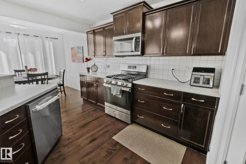 The kitchen features dark wood cabinetry, stainless steel appliances, white countertops, and hardwood flooring - 1115 61 Street, Edmonton, AB - Indoor Photo Showing Kitchen