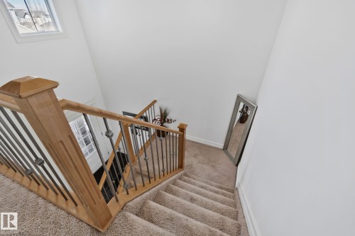 Staircase featuring light wood banisters with dark metal spindles and carpeted treads - 1115 61 Street, Edmonton, AB - Indoor Photo Showing Other Room
