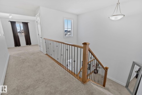 The property features a staircase with a wooden handrail and black metal balusters, and a carpeted landing - 1115 61 Street, Edmonton, AB - Indoor Photo Showing Other Room