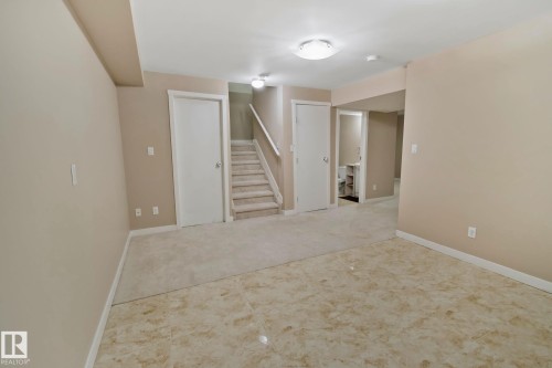 Spacious interior area featuring a combination of carpet and tiled flooring, with light-colored walls and white trim - 1115 61 Street, Edmonton, AB - Indoor Photo Showing Other Room