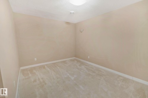 This room features light-colored walls and carpeting, with a textured ceiling and baseboards - 1115 61 Street, Edmonton, AB - Indoor Photo Showing Other Room