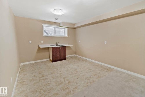 This versatile room features neutral-toned walls, a sink with a dark wood-look cabinet, and a window providing natural light - 1115 61 Street, Edmonton, AB - Indoor