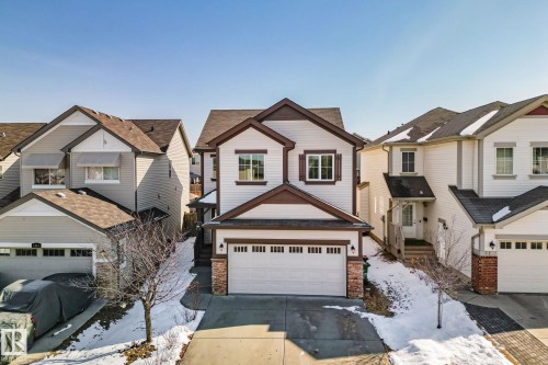 The property features a two-story exterior with white siding and dark trim, a two-car garage, and a paved driveway - 1115 61 Street, Edmonton, AB - Outdoor With Facade