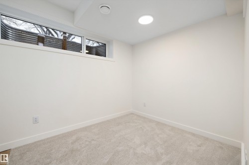 Neutral wall finishes, light-colored carpeting, recessed ceiling lighting, and a horizontal window with window well - 11418 96 Street, Edmonton, AB - Indoor Photo Showing Other Room