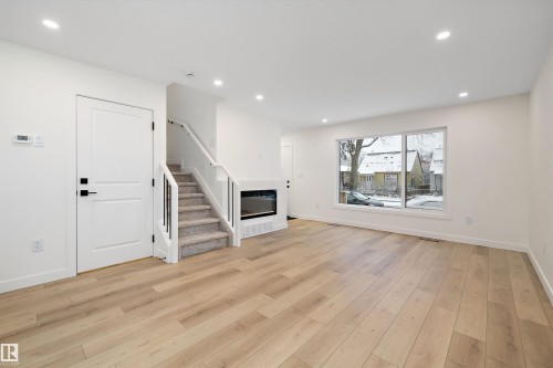 Spacious living area featuring light wood-finish flooring and recessed lighting - 11418 96 Street, Edmonton, AB - Indoor With Fireplace