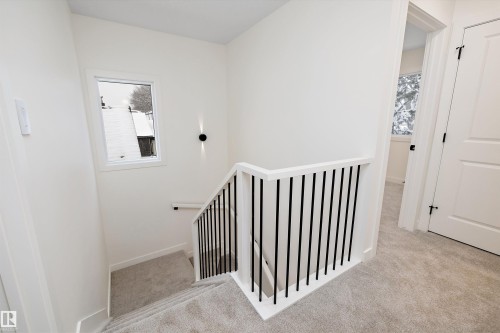 Staircase featuring contemporary black vertical balusters and white handrails - 11418 96 Street, Edmonton, AB - Indoor Photo Showing Other Room