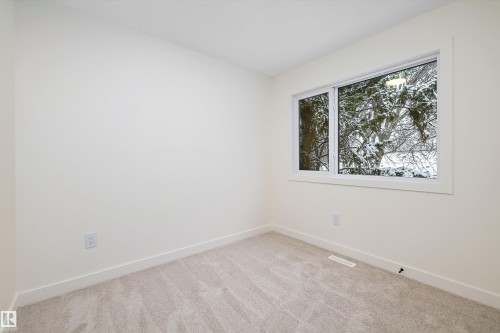 Room featuring a large window with white trim, light-colored walls, and neutral carpeting - 11418 96 Street, Edmonton, AB - Indoor Photo Showing Other Room
