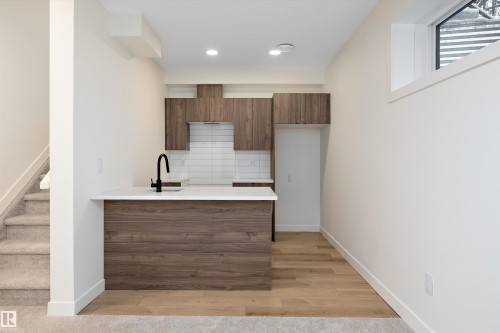 Modern kitchenette featuring wood-finish cabinetry, a white countertop, and a matte black faucet - 11918 93 Street, Edmonton, AB - Indoor Photo Showing Kitchen